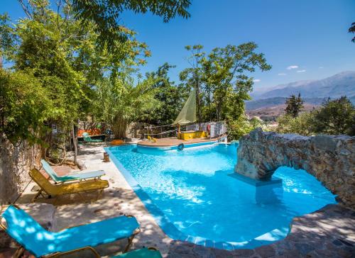 a swimming pool with chairs and a stone wall at Malaxiana Houses in Maláxa