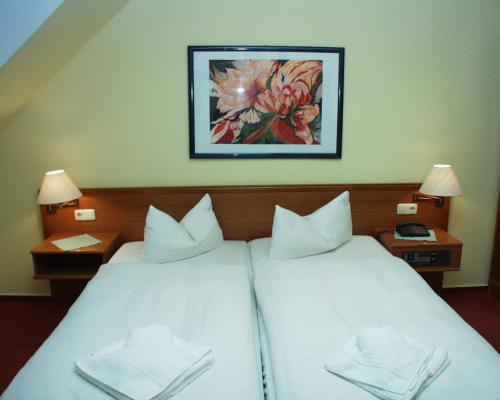 a bedroom with a white bed with a painting on the wall at Hotel Deutscher Hof in Bad Wilsnack