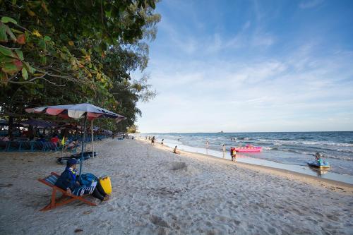 a person sitting in a chair under an umbrella on a beach at Grandblue Condominium 708 in Ban Nam Lai Ta Tum