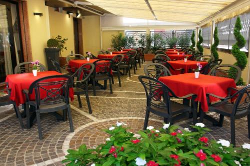 ein Restaurant mit roten Tischen, Stühlen und Blumen in der Unterkunft Hotel Colorado in Sottomarina