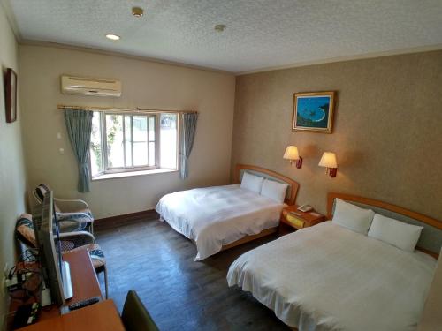 a hotel room with two beds and a window at Fun Chen Resort Hotel in Liugui