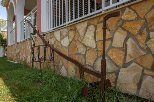 a stone wall with a metal railing next to a building at Maria Studios in Keri