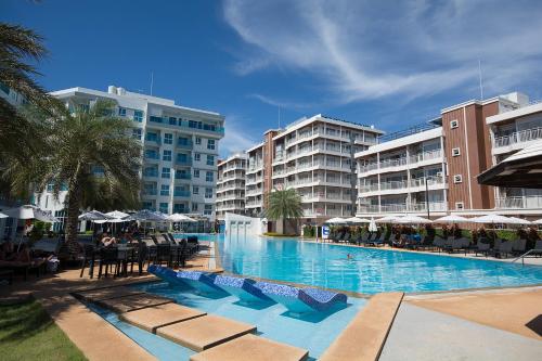 una piscina con sillas, sombrillas y edificios en GrandBlue Condo 102 by malai, en Mae Pim