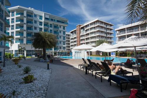 a woman laying in lounge chairs next to a swimming pool at GrandBlue Condo 102 by malai in Mae Pim