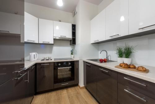 una cocina con electrodomésticos negros y armarios blancos en Wola Park - Obozowa 16 P&O Apartments, en Varsovia