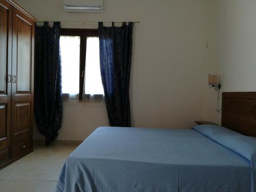 a bedroom with a blue bed and a window at Agriturismo Sa Conca Ruia in Orosei