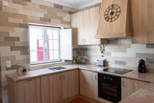 a kitchen with wooden cabinets and a clock on the wall at A Casa da Avó Ana in Arneiro das Milhariças