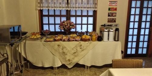 een tafel met een witte tafeldoek met voedsel erop bij Pissoloto Hotel in Sertanópolis