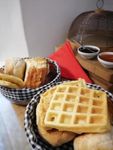 a table with waffles and bread and a basket of waffles at Casas de Incensos - TER -TA in Pontas Negras