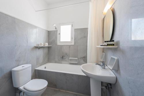 e bagno bianco con vasca, servizi igienici e lavandino. di Narges Hotel ad Aliki