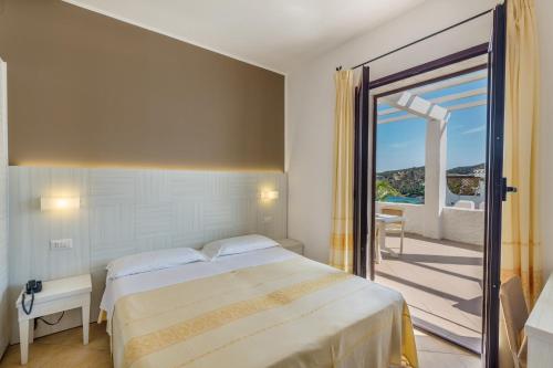 a bedroom with a bed and a door to a balcony at Hotel Mon Repos in Baja Sardinia
