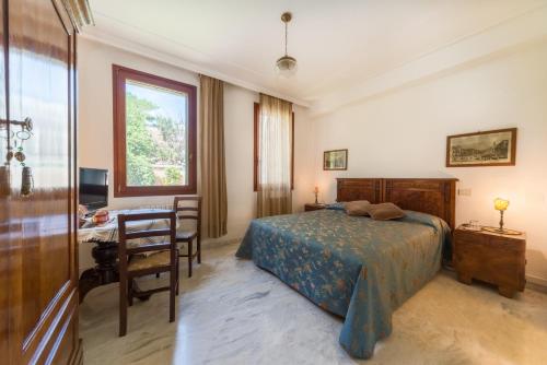 a bedroom with a bed and a desk and a window at B&B Casa Baseggio in Venice