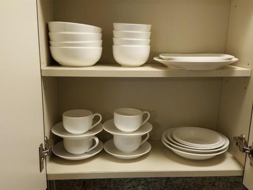 a shelf with plates and cups and dishes on it at Haeundae Bada Condo in Busan
