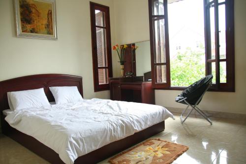 a bedroom with a bed and a chair and windows at Hạ Long Lily Homestay in Ha Long