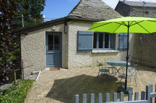 a green umbrella and a table in front of a house at La P'tite Maison in Saint-Hostien