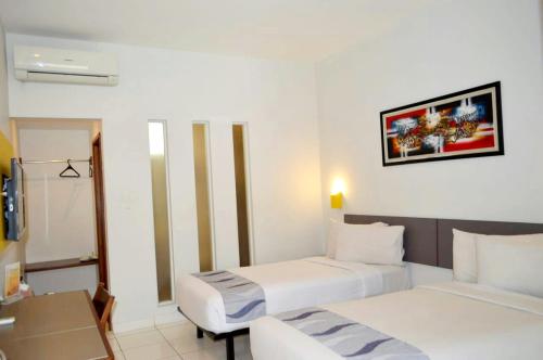 a hotel room with two beds and a desk at Hotel Koening in Cirebon