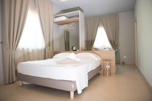 a bedroom with a large white bed and a mirror at L'Albero in Porto Empedocle