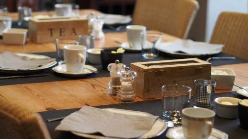 una larga mesa de madera con platos y vasos. en B&B Villa Des Raisins, en Brujas