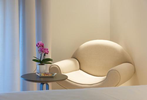 a chair sitting next to a table with a vase of flowers at Hotel Ristorante Sogno in San Felice del Benaco