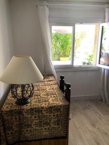 une lampe assise sur une table dans une pièce avec deux fenêtres dans l'établissement villa tsétsé, à Montpellier