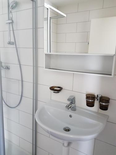 a white bathroom with a sink and a shower at Swiss Chalet Holidays Ringgenberg in Ringgenberg