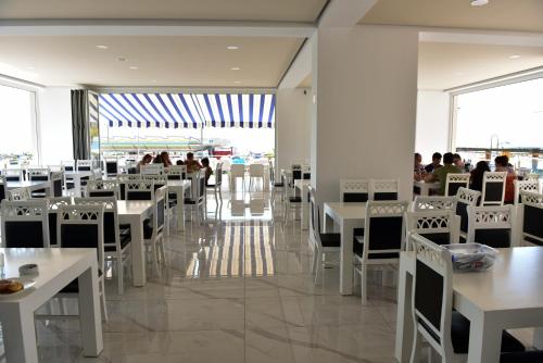 a dining room with white tables and white chairs at Hotel Fredi Shengjin in Shëngjin