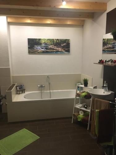 a bathroom with a bath tub and a sink at Ferienwohnung ALEXA in Walshausen