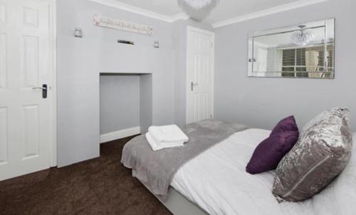 Schlafzimmer mit einem Bett mit lila Kissen und einem Spiegel in der Unterkunft Imperial House Holiday Let in Herne Bay