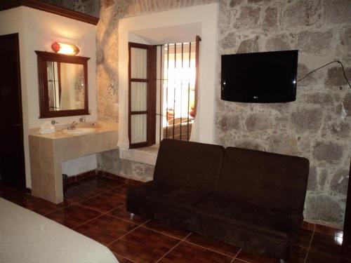 a living room with a couch and a tv on a stone wall at Mansion Serrano Hotel in El Fuerte