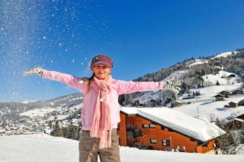 a girl standing in the snow with her arms out at Résidence Azureva La Clusaz les Aravis in La Clusaz