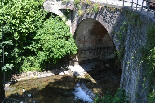 an old stone bridge with a river under it at La Limonaia di Casagrande in Barga
