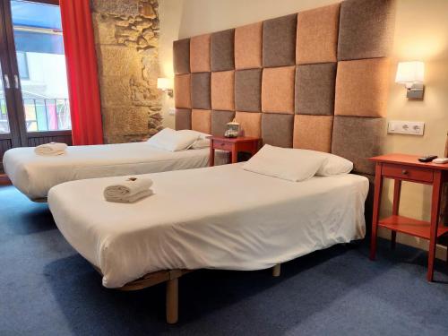 a hotel room with two beds and two tables at Iturrienea Ostatua in Bilbao