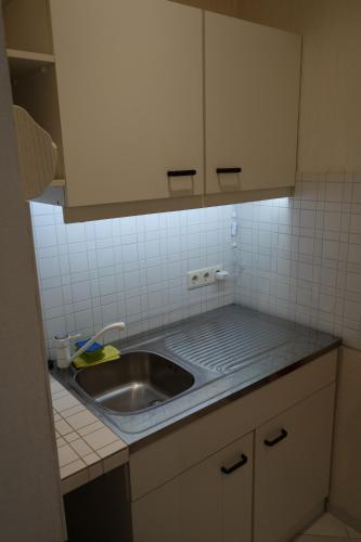 - une cuisine avec un évier et un comptoir carrelé dans l'établissement Fewo Oechler, à Seelbach