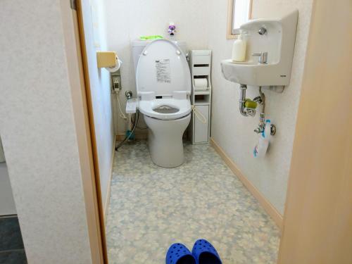 a bathroom with a toilet and a sink and a pair of shoes at Duplex Makishi in Makishimachi