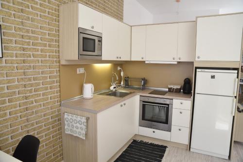 a kitchen with white cabinets and a brick wall at Studio Toni in Sliven