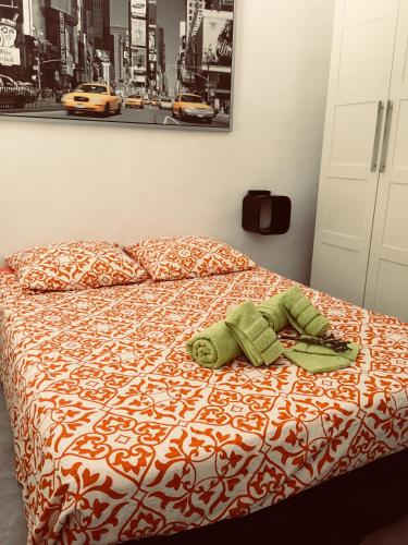 un animal fourré vert se pose sur un lit dans l'établissement Le Suffren, studio classé ventilé ,wifi, à 100 m de la plage, à Toulon