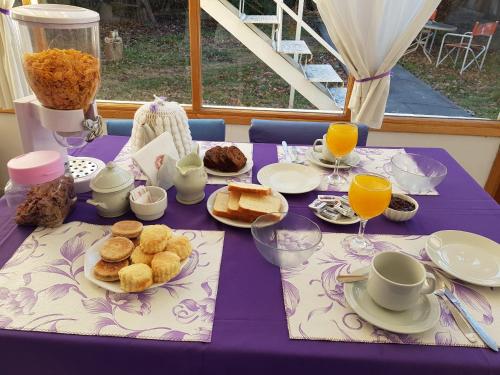 una mesa púrpura con comida y vasos de zumo de naranja en Hostería Gwesty Plas y Coed en Gaiman