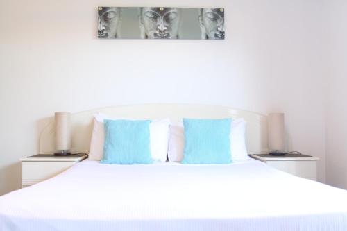 a bedroom with a white bed with blue pillows at Koala Cove Holiday Apartments in Gold Coast