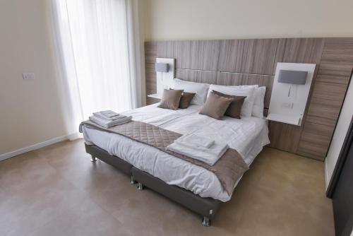 une chambre avec un grand lit avec des draps et des oreillers blancs dans l'établissement 3 Amici Suites, à Vérone