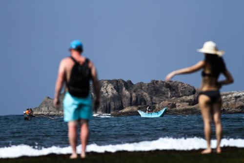 a man and a woman standing on the beach at Hikka Sands & SPA in Hikkaduwa