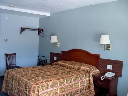 Una habitación de hotel con una cama y un teléfono sobre una mesa. en Economy Inn, en Willows