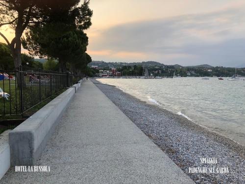a sidewalk next to a body of water at Hotel La Bussola in Padenghe sul Garda