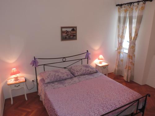 een slaapkamer met een bed met een paarse sprei en 2 lampen bij Apartment Pera in Split