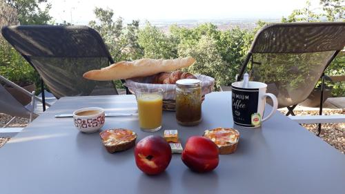 Una mesa con un desayuno de pan, manzanas y jugo de naranja. en Maison d'hôtes la Garenne, en Puyloubier