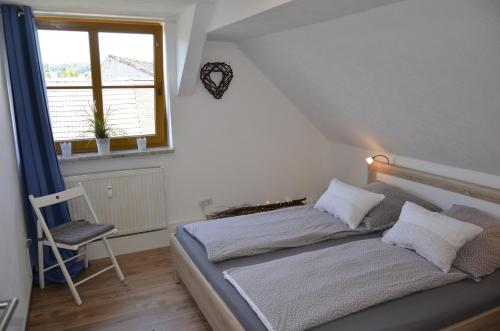 a bedroom with a bed with a chair and a window at Ferienwohnung Lohra in Lohra
