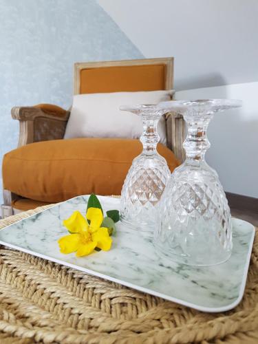 two glass vases and a yellow flower on a tray at Domaine de la Fauvriere in Sainte-Honorine-de-Ducy