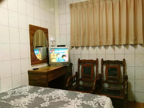 a bedroom with a bed and a mirror and a television at Qun Feng Hotel in Fenchihu