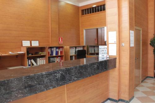トレモリノスにあるNch Hotel Torremolinosの木製の壁と大理石のカウンターがある図書室