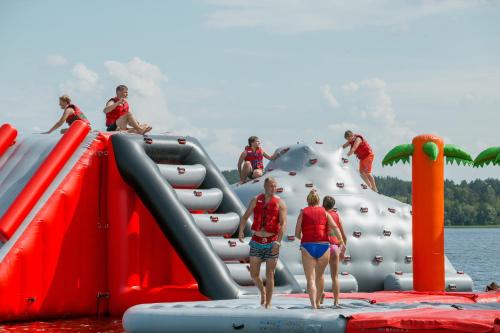 a group of people playing on an inflatable play structure in the water at Camping Pod in Zarasai
