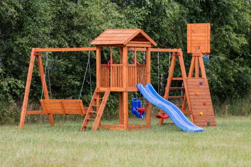 a wooden play set with a slide and a swing at Windmill vacation home in Ledzin near Baltic Sea in Niechorze